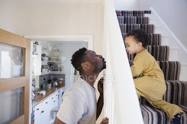 Playful father and toddler son crawling up stairs — Stock Photo
