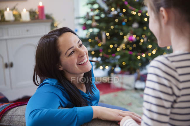 Усміхнене матері розмови з дочкою в різдвяні вітальні — стокове фото