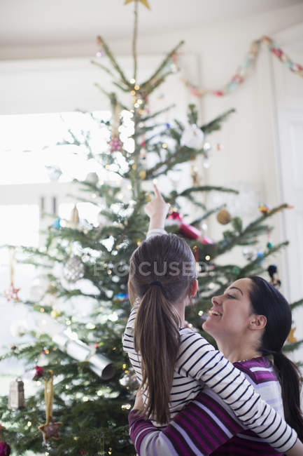 Affectionate mother and daughter looking up at Christmas tree — Stock Photo