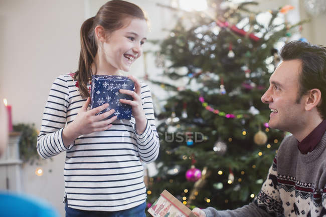 Padre e hija con regalos delante del árbol de Navidad - foto de stock