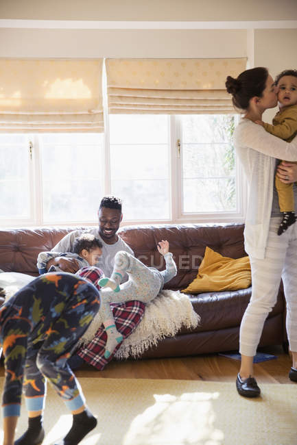 Грайлива багатоетнічна сім'я в піжамі в сонячній вітальні — стокове фото