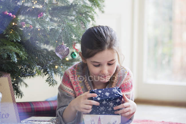 Chica curiosa sosteniendo regalo de Navidad - foto de stock