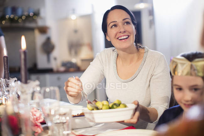 Sorrindo mulher servindo brotos de Bruxelas na mesa de jantar de Natal — Fotografia de Stock