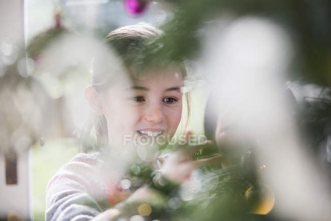 Улыбающаяся девушка украшает елку — стоковое фото