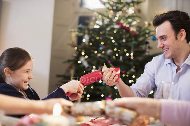 Father and daughter pulling Christmas cracker at dinner table — Stock Photo