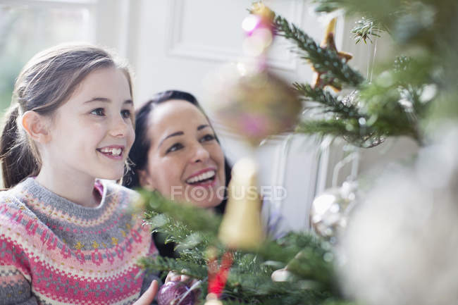 Счастливая мать и дочь украшают елку — стоковое фото