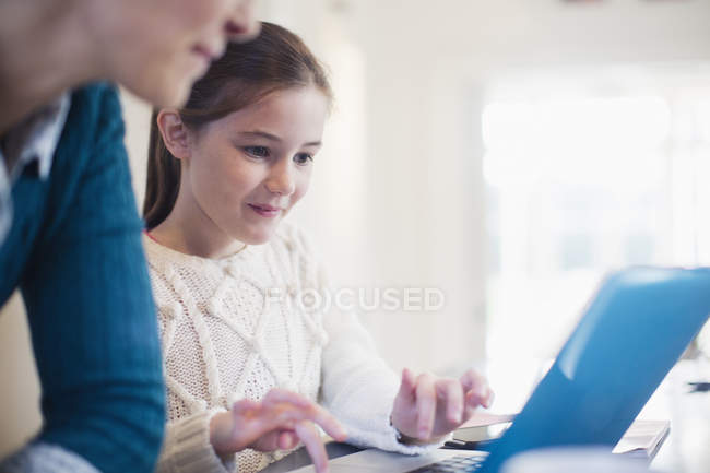 Chica curiosa y la madre usando el ordenador portátil - foto de stock