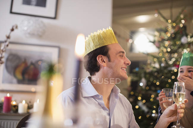 Happy father and daughter in paper crowns drinking water and champagne at candlelight Christmas dinner — Stock Photo