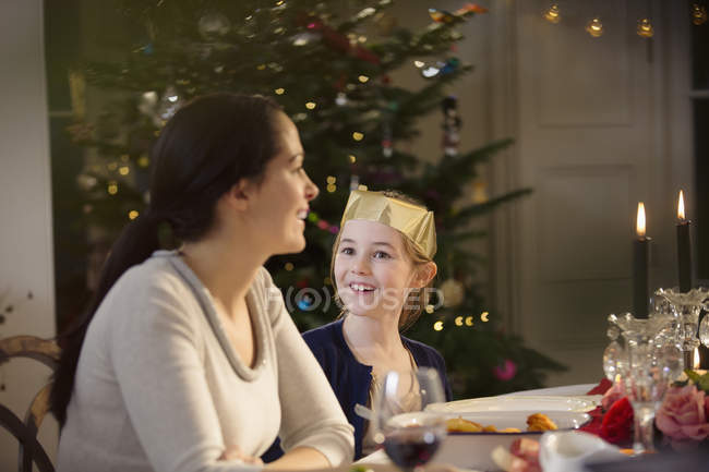Happy mother and daughter in paper crown at candlelight Christmas dinner table — Stock Photo