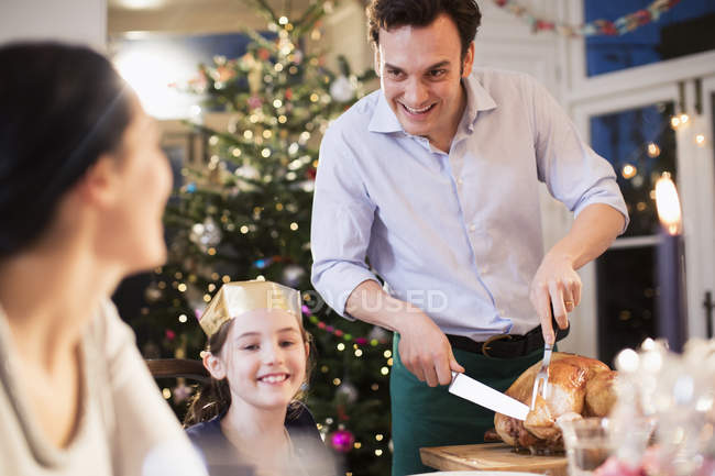Семья вырезает рождественскую индейку, наслаждаясь обедом — стоковое фото