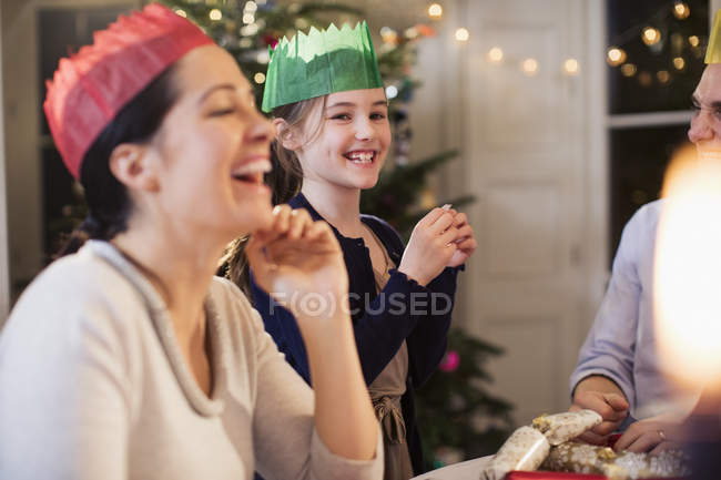 Glückliche Familie in Papierkronen lacht beim Weihnachtsessen — Stockfoto