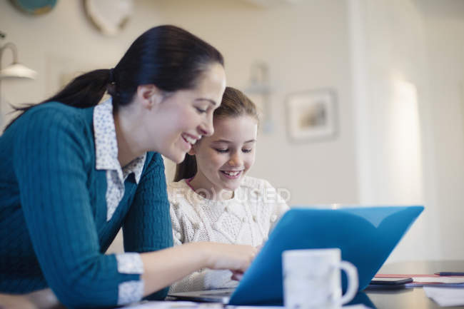 Feliz madre e hija usando el ordenador portátil - foto de stock