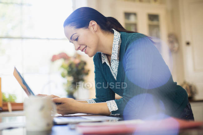 Mujer usando portátil en la cocina - foto de stock