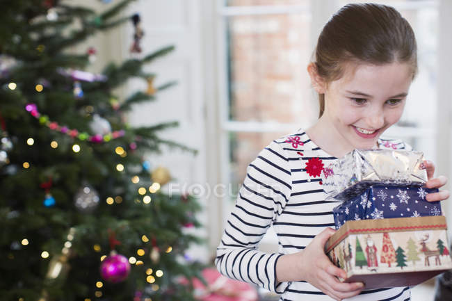 Sorrindo, menina ansiosa reunindo presentes de Natal na sala de estar — Fotografia de Stock
