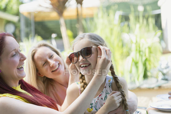 Лесбийская пара и дочь играют в солнечные очки на патио — стоковое фото
