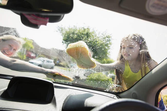 Mother and daughter washing car windshield — Stock Photo