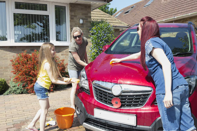 Lésbicas casal e filha lavar carro na entrada ensolarada — Fotografia de Stock