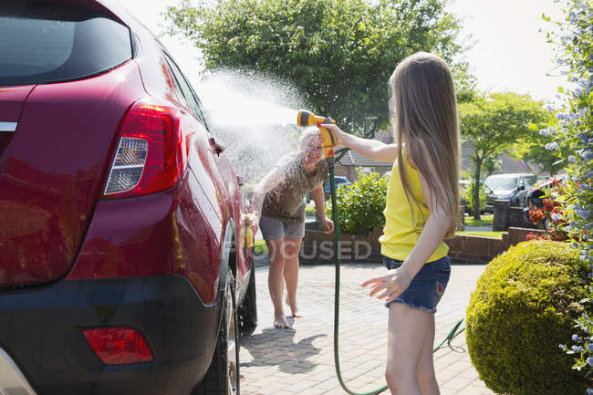 Mother and daughter washing car in sunny driveway — Stock Photo