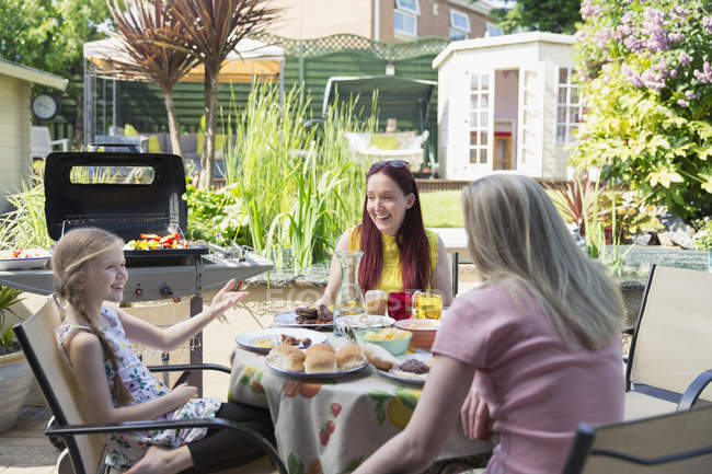 Lesbian couple and daughter enjoying barbecue lunch on summer patio — Stock Photo