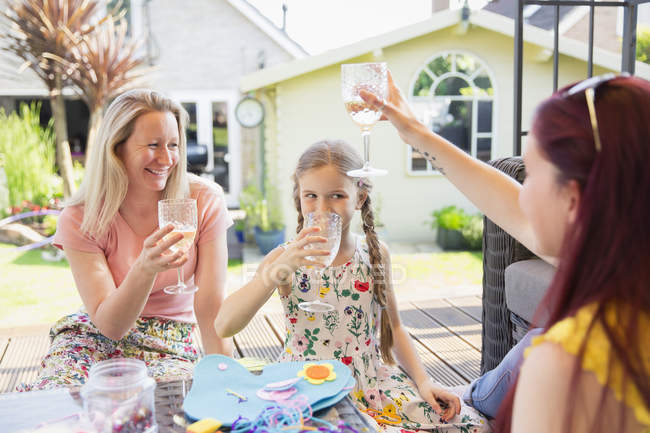 Lesbian couple and daughter drinking on sunny patio — Stock Photo