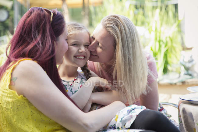 Affectionate lesbian couple kissing daughter — Stock Photo