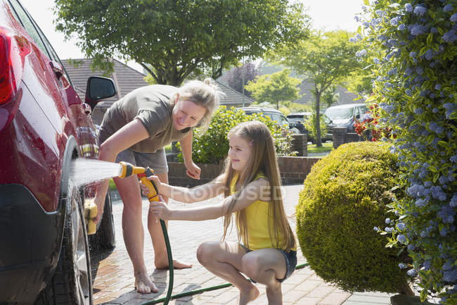 Mother and daughter washing car in sunny driveway — Stock Photo