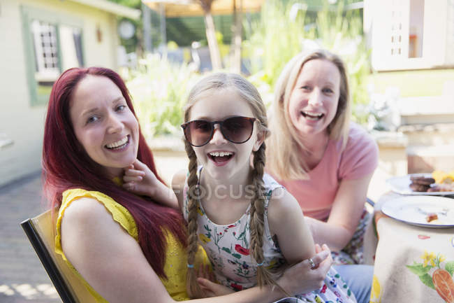 Portrait happy lesbian couple and daughter with sunglasses on patio — Stock Photo