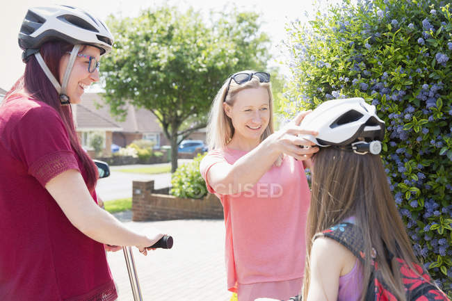 Lesbian couple and daughter riding scooters in sunny driveway — Stock Photo