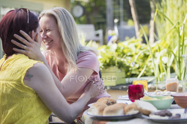 Liebevolles lesbisches Paar genießt Mittagessen am Terrassentisch — Stockfoto