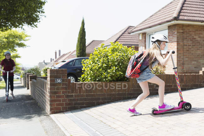 Menina montando scooter na entrada ensolarada — Fotografia de Stock