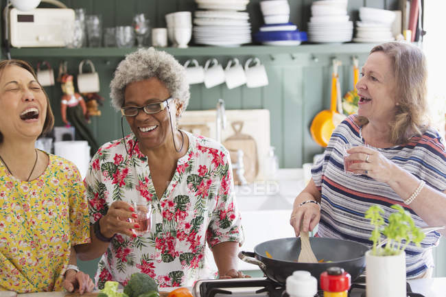 Счастливые активные пожилые женщины готовят на кухне — стоковое фото