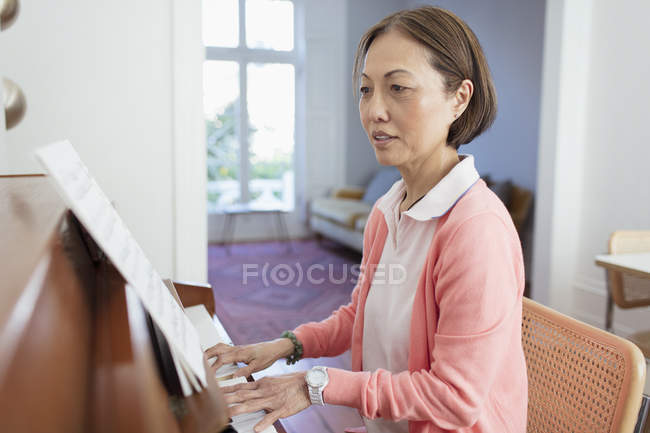 Donna anziana attiva che suona il pianoforte a casa — Foto stock