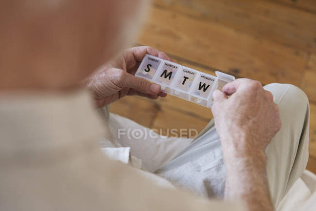 Hombre mayor con caja de pastillas en casa - foto de stock