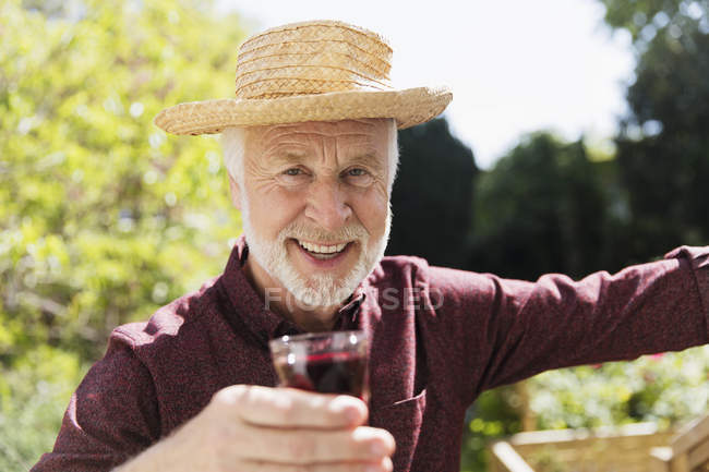 Retrato confiante sênior homem bebendo vinho tinto no jardim — Fotografia de Stock