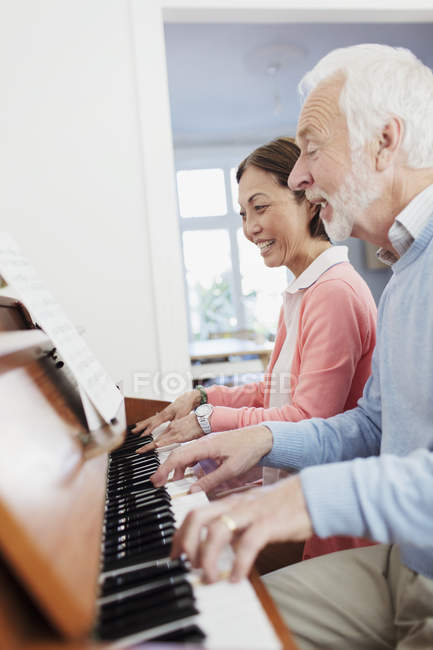 Активная старшая пара играет на пианино — стоковое фото