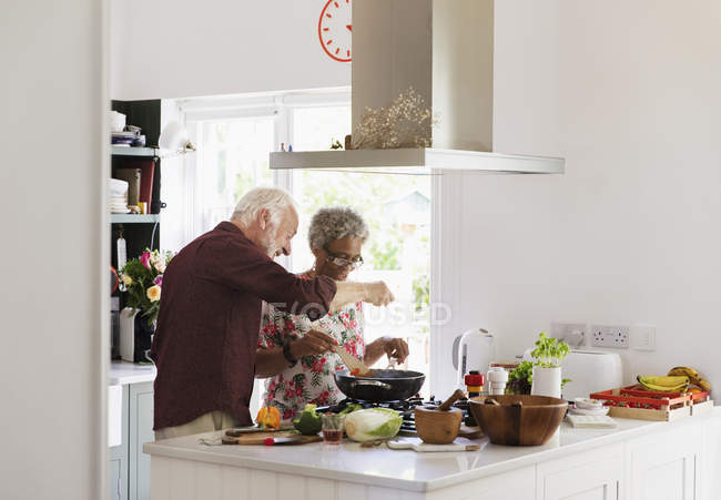 Active senior couple cooking in kitchen — Stock Photo