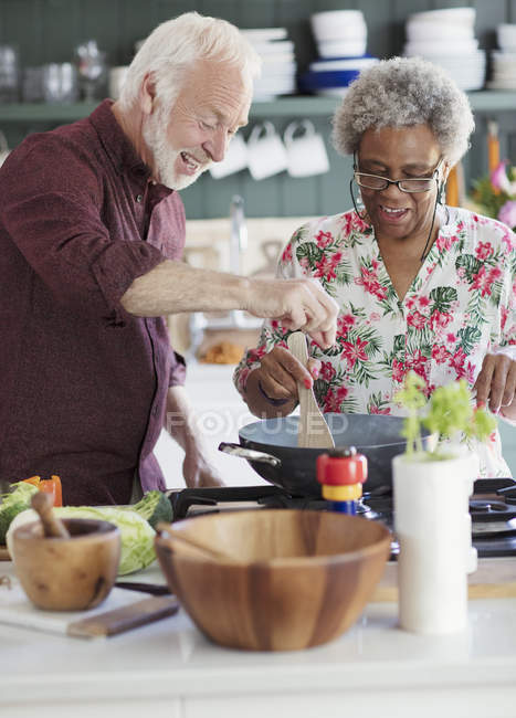 Активная пара пожилых людей приготовление пищи на кухне — стоковое фото