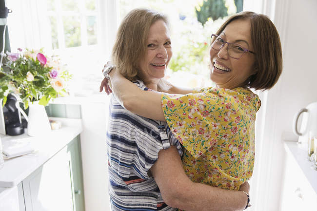 Любящие портреты пожилые лесбиянки обнимаются на кухне — стоковое фото