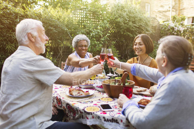 Amigos seniores ativos brindando copos de vinho rosa na festa do jardim — Fotografia de Stock