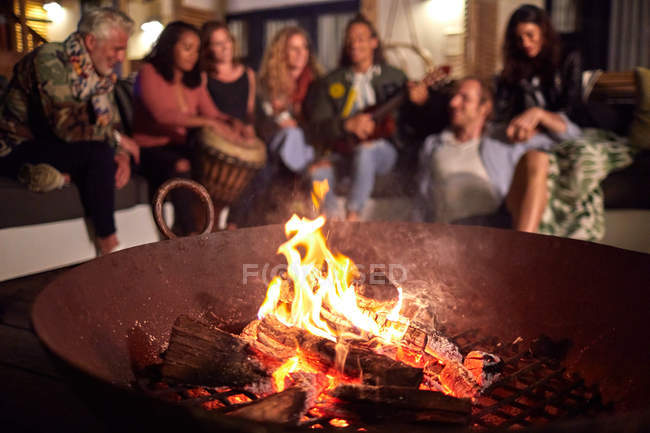 Friends hanging out, playing music on patio next to fire pit — Stock Photo