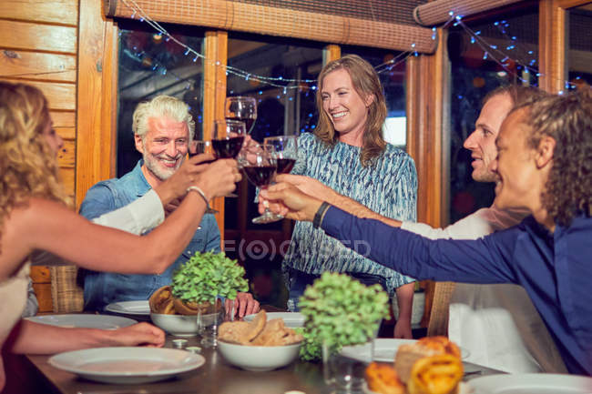 Friends celebrating, drinking red wine and enjoying dinner in cabin — Stock Photo