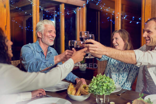 Amigos comemorando, bebendo vinho tinto e jantando na cabine — Fotografia de Stock