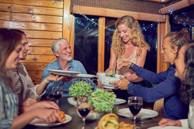 Frau serviert Freunden Abendessen am Kabinentisch — Stockfoto