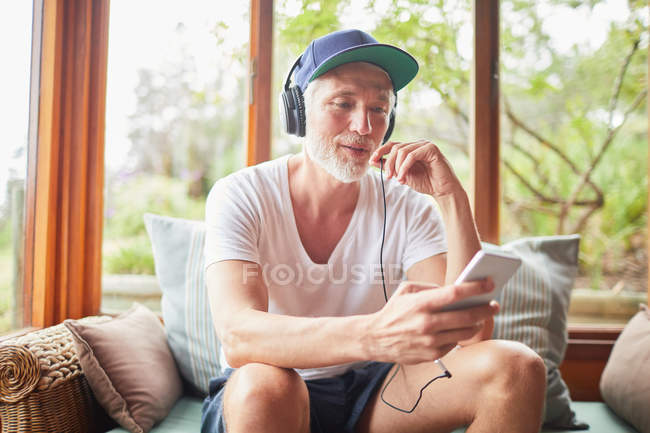 Homem com fones de ouvido e mp3 player ouvindo música na sala de estar — Fotografia de Stock