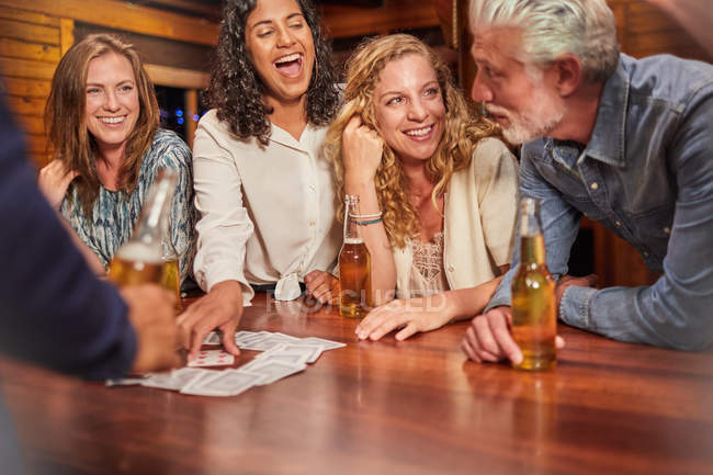 Friends playing card game at cabin table — Stock Photo