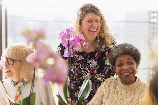 Щасливий інструктор і активні літні люди насолоджуються класом аранжування квітів — стокове фото