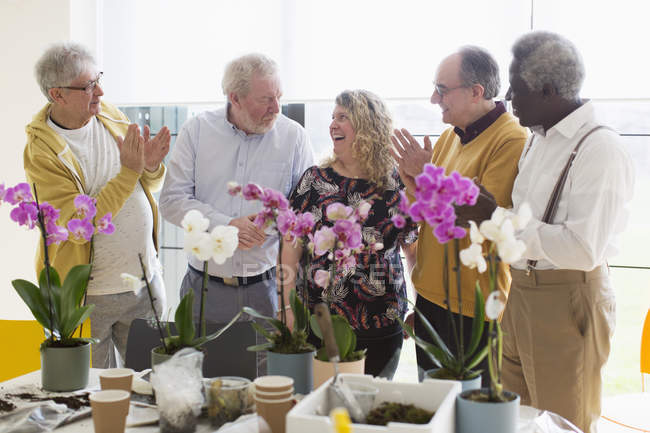 Активні старші чоловіки плескають для інструктора жіночої статі в класі квіткових композицій — стокове фото