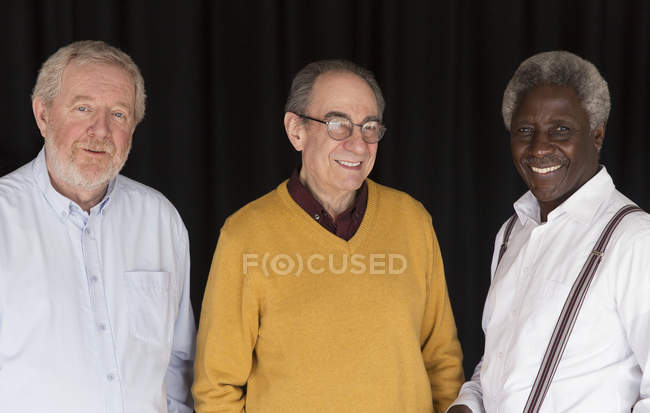 Portrait confident senior men posing against black background — Stock Photo