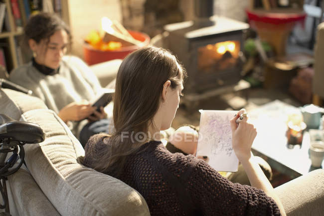 Giovane donna disegno, schizzo in blocco note in soggiorno — Foto stock