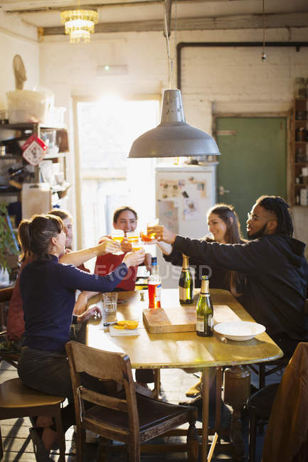 Jovens amigos adultos brindando coquetéis na mesa da cozinha do apartamento — Fotografia de Stock